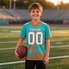 Custom Aqua - White - Orange Graphic Splash Pattern Football Jersey – youth size worn by a kid