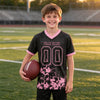 Custom Black - Light Pink Graphic Splash Pattern Football Jersey – youth size worn by a kid